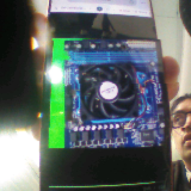 The same fan photo as the E8 camera saw it on a phone screen: 160 pixels, glare, colour shift and the presenter's hand in view